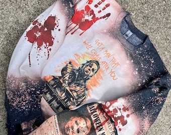 Könnte beinhalten: Ein gebleichtes schwarzes Sweatshirt mit einer Grafik einer maskierten Figur, die ein Messer hält, einem roten Handabdruck, dem Text "Get a man that will chase after you" und "Halloween Massacre" sowie einem Zeitungsdruck eines Gesichts.