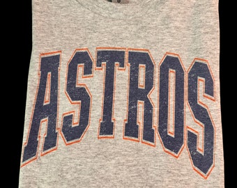 May include: Gray t-shirt with a navy blue and orange "ASTROS" graphic printed on the front.