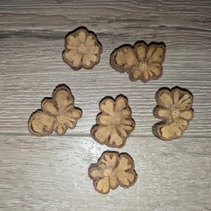 Puede incluir: Seis adornos de madera de color marrón en forma de flor con un acabado de veta de madera natural.