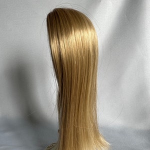 May include: A long, straight, light blonde wig on a white mannequin head with a decorative base.