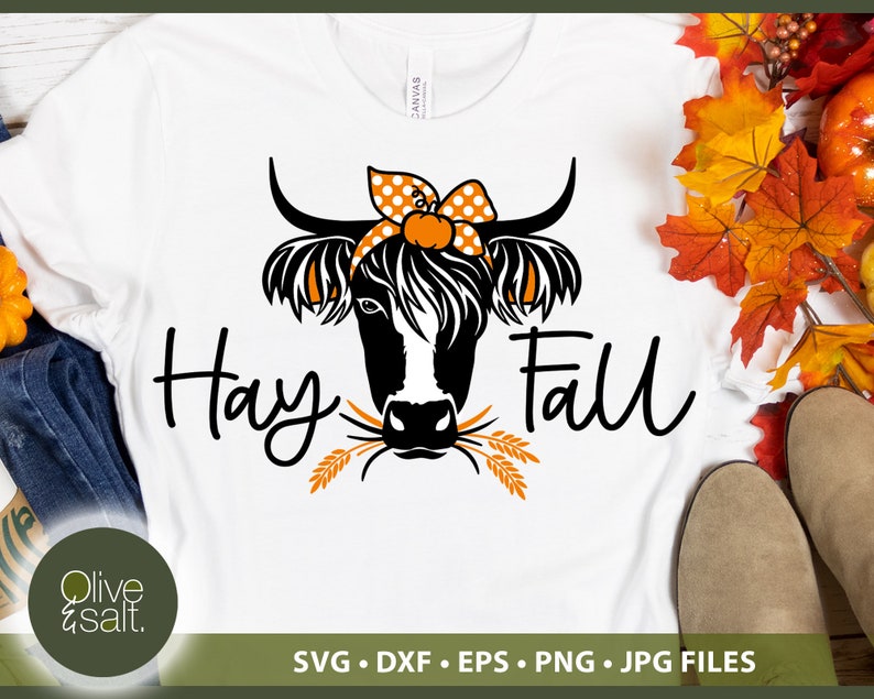 Puede incluir: Camiseta blanca con una ilustraci&oacute;n en blanco y negro de una vaca con un lazo de lunares y una calabaza. El texto "Hay Fall" est&aacute; escrito en negro debajo de la vaca.