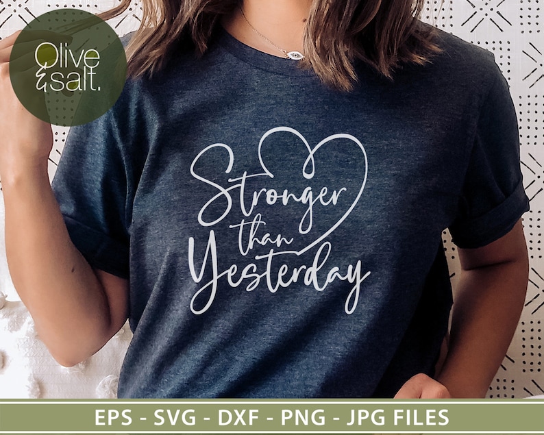Pu&ograve; includere: Una maglietta blu scuro con un cuore bianco e il testo "Stronger than Yesterday" stampato sul davanti.