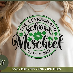 May include: A cream-colored t-shirt featuring a circular design with the text "THE LEPRECHAUN School OF Mischief CLASS OF 2023". The design includes green shamrocks and a green and black border. The bottom of the shirt has the text "SVG &bull; DXF &bull; EPS &bull; PNG &bull; JPG FILES".