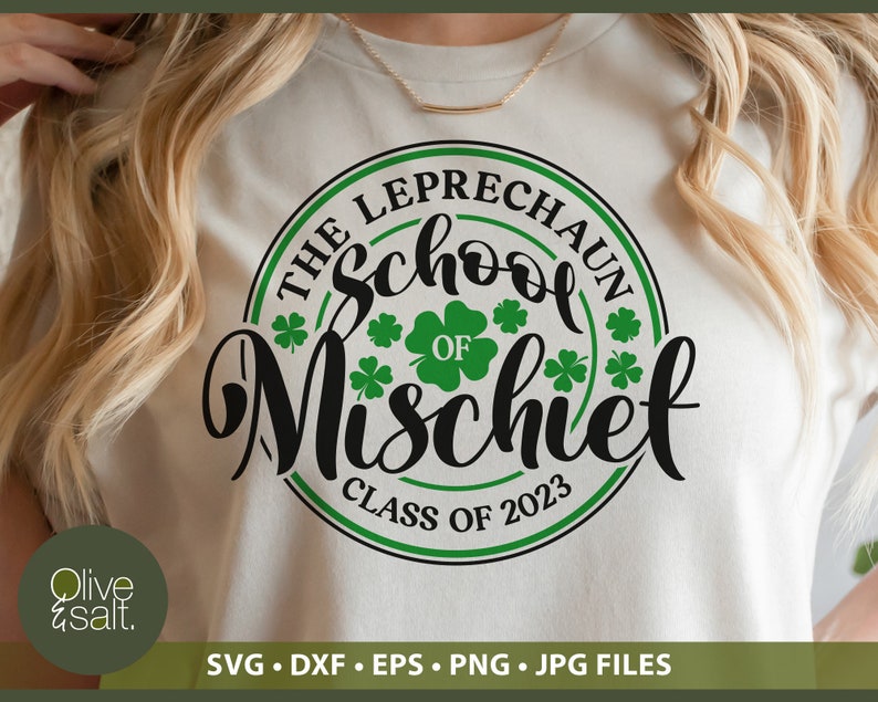 May include: A cream-colored t-shirt featuring a circular design with the text "THE LEPRECHAUN School OF Mischief CLASS OF 2023". The design includes green shamrocks and a green and black border. The bottom of the shirt has the text "SVG &bull; DXF &bull; EPS &bull; PNG &bull; JPG FILES".