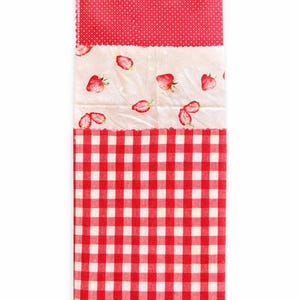 May include: A stack of three reusable food wraps with different patterns. The top wrap is red with white polka dots, the middle wrap has a strawberry print, and the bottom wrap is red and white checkered.