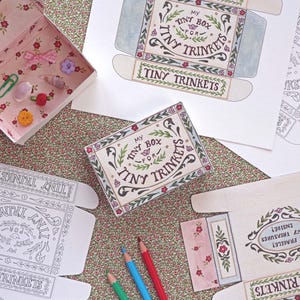 May include: A collection of paper craft templates for small boxes featuring floral borders and the text My Tiny Box For Tiny Trinkets. One assembled box contains small items like a pink bow, a green paperclip, and colorful buttons.