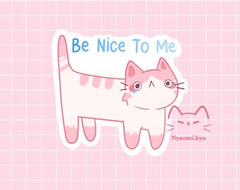 May include: A white and pink cat illustration with the text "Be Nice To Me" in blue. The cat has pink ears, paws, and stripes, with tear drops. A smaller cat illustration is below with the text "Nyaomi.kyu".