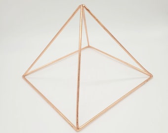 May include: A rose gold wire pyramid, a geometric shape, with a square base.