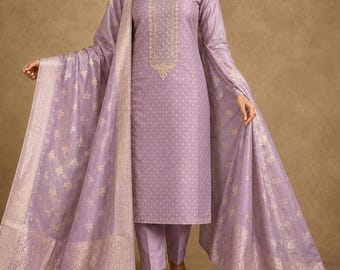 Puede incluir: Una túnica lavanda de corte recto y manga larga con un sutil patrón de puntos y un intrincado bordado dorado a lo largo del escote central, combinada con pantalones lavanda a juego y un gran pañuelo transparente con bordes florales dorados.