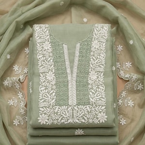 May include: A sage green fabric set featuring a tunic with a V-neckline and intricate white floral embroidery along the front panel. The set includes a matching sheer sage green dupatta with white floral embroidery along the scalloped edges.