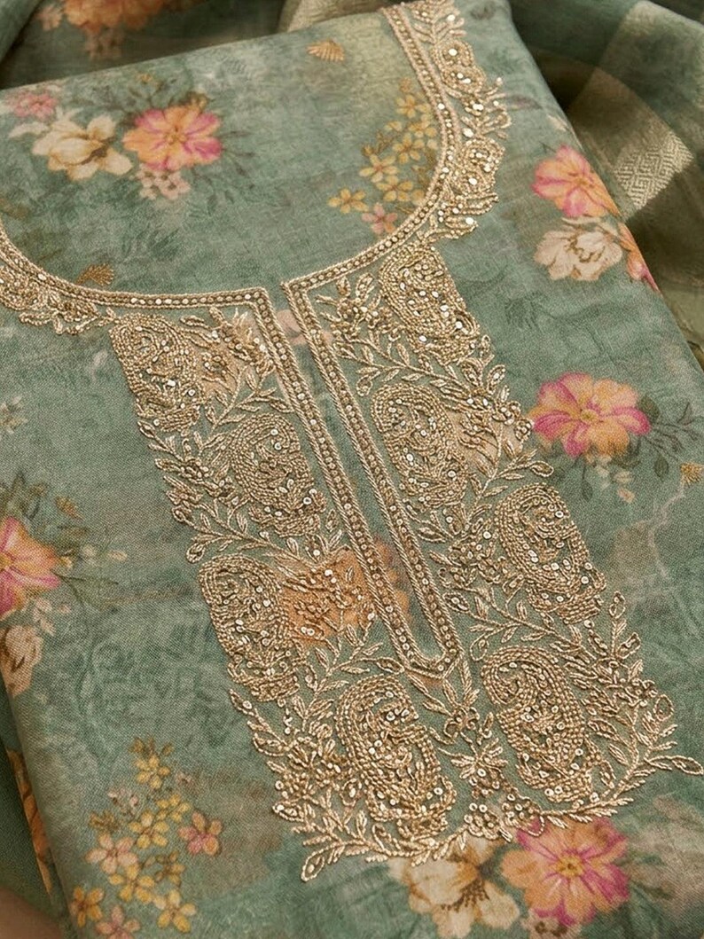 May include: A sage green fabric featuring a floral print with pink and yellow flowers. The neckline and front panel are decorated with intricate gold embroidery, including paisley motifs and small metallic sequins throughout the design.