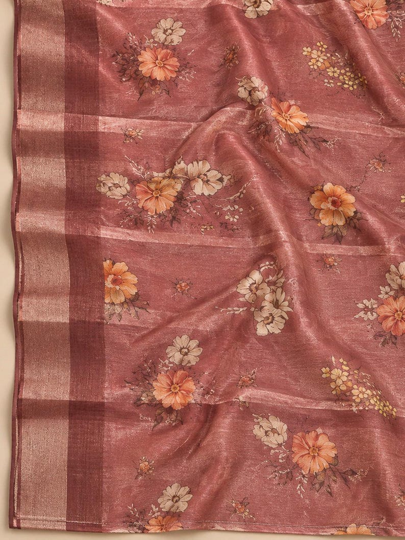 May include: A dusty rose fabric featuring a floral pattern with orange and cream-colored blossoms. The textile has a subtle sheen and a visible weave, with a wide, vertical border on the left side composed of alternating dark and light bands.