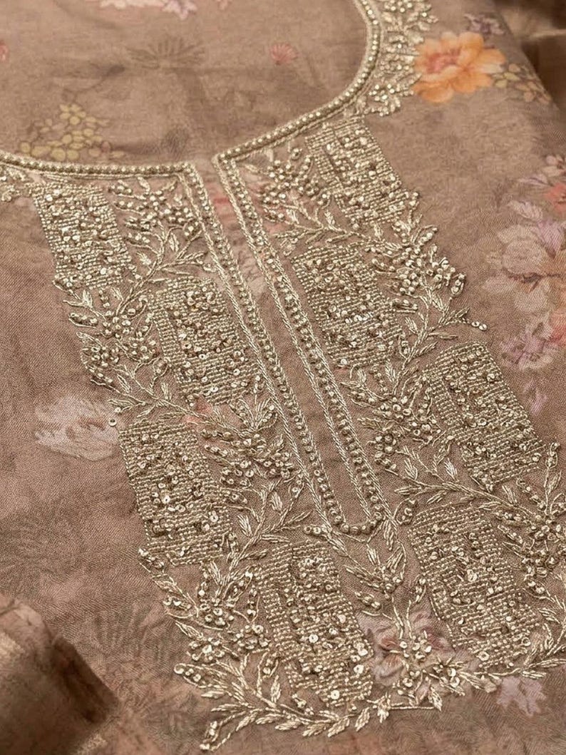 May include: A taupe-colored fabric garment featuring a floral print in muted tones of pink and orange. The neckline and front placket are heavily embellished with intricate silver-toned metallic embroidery, beadwork, and sequins in a floral pattern.