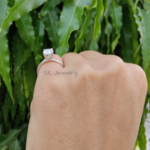 May include: A silver ring with a large, clear, round gemstone. The ring is on a person's finger. The text "sk jewelry" is visible on the ring.