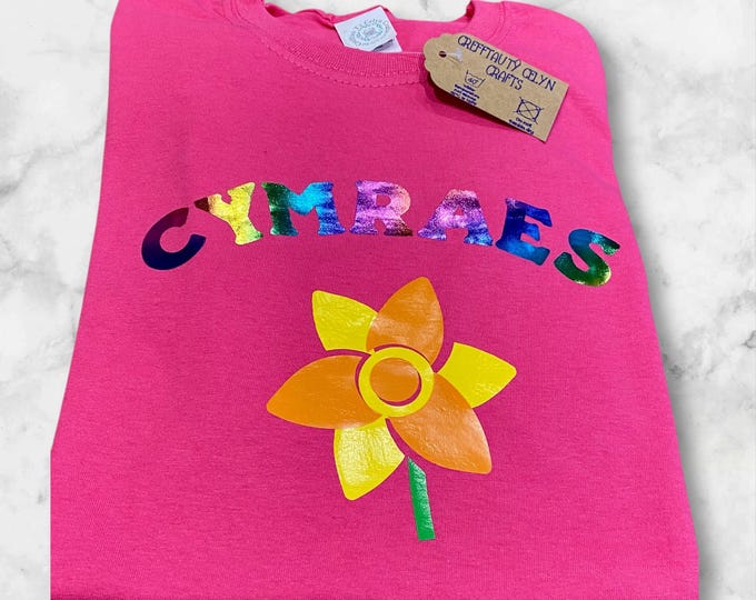 Crys T pinc ‘Cymraes’ i ferched efo llun cennin pedr/ Pink Welsh girls T shirt with the word Cymraes (Welsh(girl)) & picture of daffodil.