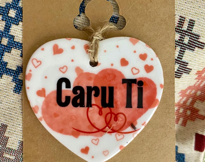 Addurn calon seramig i’w hongian ar efo dyluniad ‘Caru Ti’ ceramic hanging heart with the Welsh words ‘Caru Ti’(Love you).
