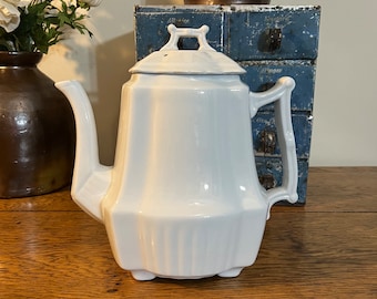 May include: White porcelain coffee pot with a lid and a handle. The pot has a fluted design and sits on three small feet.