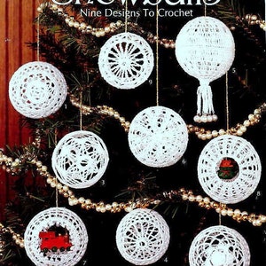 May include: Nine crochet snowball ornament designs for Christmas. The ornaments are white and feature different patterns, including snowflakes, stars, and a train. The ornaments are hanging on a Christmas tree.