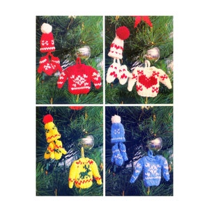 May include: Four knitted Christmas decorations, each featuring a different colour and design. The decorations are a red sweater with white snowflakes, a white sweater with a red heart, a yellow sweater with a green reindeer, and a blue sweater with white snowflakes. Each decoration also includes a matching knitted hat and mittens.