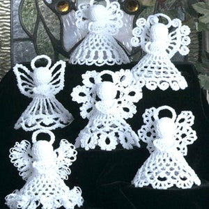 May include: Six white crocheted angel ornaments with delicate lace details. The angels are arranged on a black background.