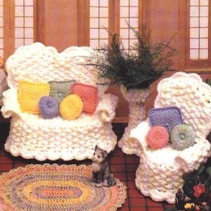 May include: A white crocheted dollhouse sofa and armchair with colorful pillows and a small crocheted rug.