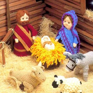 May include: A crocheted nativity scene with a brown-haired Joseph, a blue-robed Mary, and a baby Jesus in a yellow manger. There is also a brown cow, a white sheep, and a gray donkey.