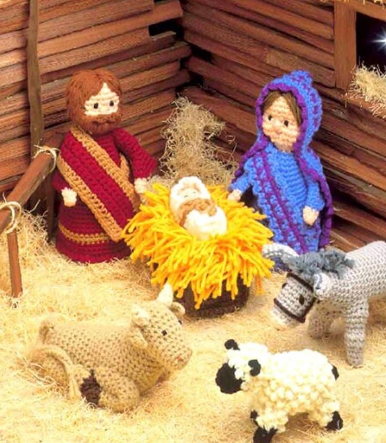 May include: A crocheted nativity scene with a brown-haired Joseph, a blue-robed Mary, and a baby Jesus in a yellow manger. There is also a brown cow, a white sheep, and a gray donkey.