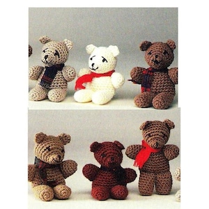 May include: A collection of seven crocheted teddy bears, each wearing a scarf. The bears are in various colors, including brown, white, and red. The bears are sitting on a white background.