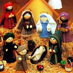 May include: Knitted nativity scene with figures of Mary, Joseph, baby Jesus, a shepherd, and three wise men. The figures are dressed in traditional clothing and are standing in front of a wooden stable.