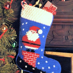 May include: A blue and white crocheted Christmas stocking with a Santa Claus design. Santa is depicted in a red suit with a white beard and hat, climbing down a brick chimney. The stocking is decorated with white snowflakes.