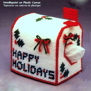 May include: White plastic canvas tissue box cover with red and green trim. The cover is decorated with a holly design and the words "Happy Holidays".