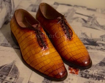 May include: A pair of brown leather oxfords with a crocodile pattern. The shoes have a lace-up closure and a pointed toe.