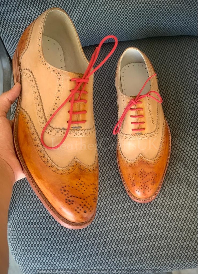 May include: Two pairs of brown leather brogue shoes with red laces. The shoes have a wingtip design and are made of distressed leather.