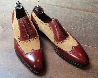 Könnte beinhalten: Ein Paar braune und beige Lederschuhe mit Flügelspitzen. Die Schuhe haben einen Schnürverschluss und eine spitze Zehenpartie.