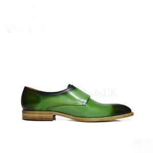 May include: Green leather dress shoes with a single buckle strap. The shoes have a brown leather sole.