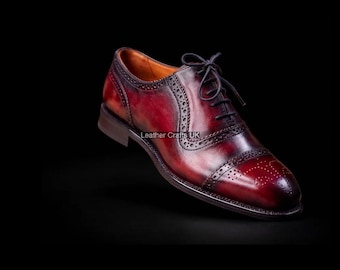 May include: A deep burgundy leather oxford shoe featuring a cap toe with decorative brogue perforations, a lace-up closure with thin dark laces, and a smooth polished finish. The text Leather Crafts UK is visible on the side of the shoe.