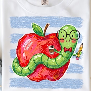 May include: A white t-shirt featuring a graphic of a green worm wearing black glasses and a red bow tie. The worm holds a coffee cup and a yellow pencil while wrapped around a large red apple. The background has horizontal light blue stripes.