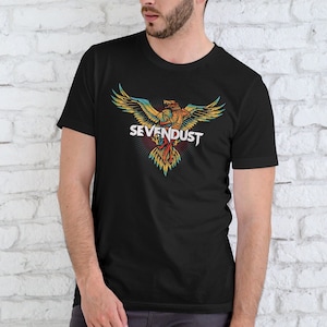 Op de afbeelding: Zwart T-shirt met een kleurrijk adelaarsontwerp en de witte tekst "SEVENDUST". De adelaar heeft gele, oranje en blauwe accenten. Het shirt heeft een ronde hals en korte mouwen.