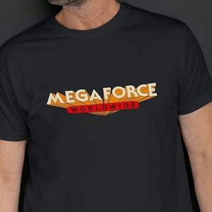 Peut inclure: Un t-shirt noir avec un graphique du texte "MEGA FORCE WORLDWIDE" en orange et rouge.
