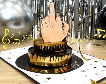 May include: A pop-up birthday card featuring a hand giving the middle finger, with a candle flame on the fingertip. The card has a two-tiered cake design with gold accents and the words "HAPPY BIRTHDAY". Musical notes and gold stars decorate the background.