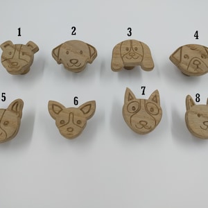 May include: Eight wooden dog head drawer pulls in various breeds. The pulls are numbered 1 through 8.