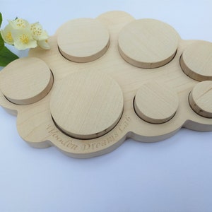 May include: Wooden cloud-shaped puzzle with six round pieces of varying sizes. The puzzle is made of light wood and has the words "Wooden Dreams Ltd" engraved on the bottom.