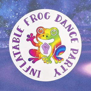May include: A round sticker with the text "INFLATABLE FROG DANCE PARTY" in purple. The sticker features a colorful rainbow frog with a raised fist. The background is a starry, purple design.