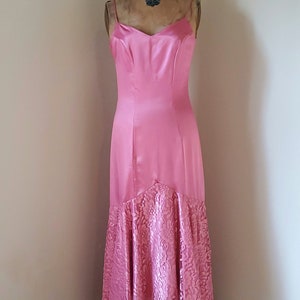 May include: A pink satin dress with a lace hem. The dress is on a dress form and has a sweetheart neckline.