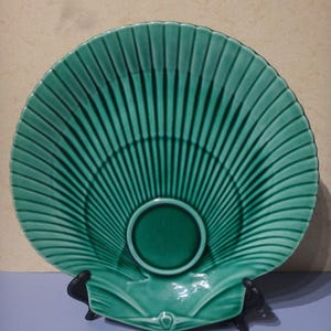 Könnte beinhalten: Ein grüner Keramikteller in Form einer Jakobsmuschel. Der Teller hat ein erhabenes Design aus Linien, die vom Zentrum ausstrahlen.