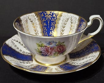 Taza y platillo de porcelana fina vintage Paragon, diseño floral azul con detalles dorados, década de 1960.