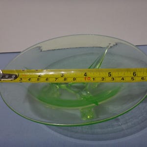 May include: A green glass divided dish with a 25.4 cm diameter. The dish has three points that come up from the center.