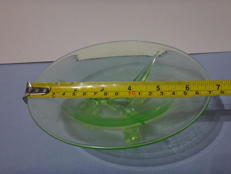 May include: A green glass divided dish with a 25.4 cm diameter. The dish has three points that come up from the center.