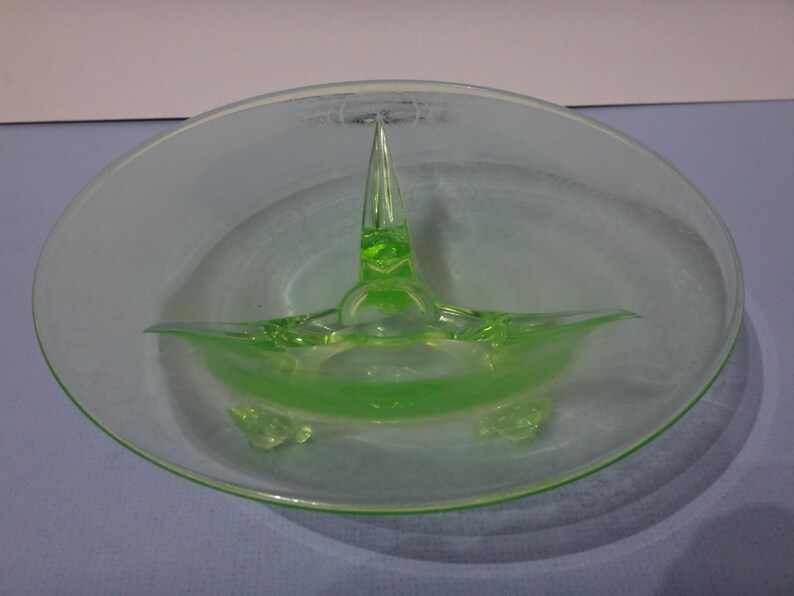 May include: A green glass bowl with three legs and a pointed centre piece. The bowl is clear and has a frosted finish.
