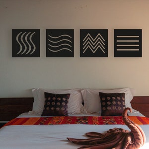 May include: A bright bedroom with a large bed. The bed has a white duvet and a decorative towel swan. There is a colourful runner and decorative pillows. Above the bed are four framed abstract art pieces. Two decorative lamps flank the bed.